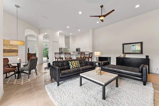 living area with light tile patterned flooring, recessed lighting, arched walkways, and ceiling fan