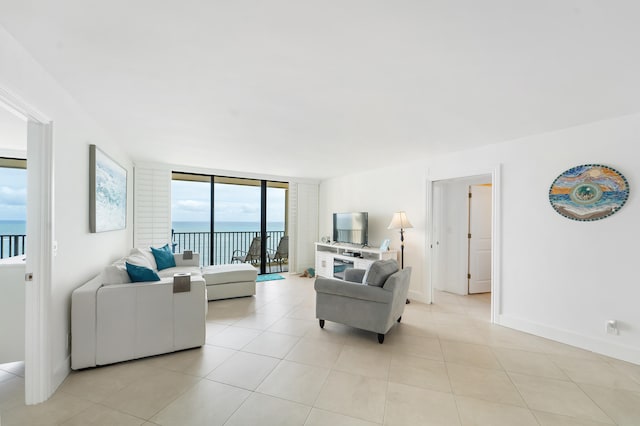 living room featuring light tile patterned floors, a water view, and expansive windows