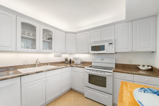 kitchen featuring white appliances, white cabinets, dark stone countertops, sink, and light tile patterned flooring