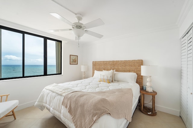 bedroom with crown molding, light tile patterned floors, a closet, a water view, and ceiling fan