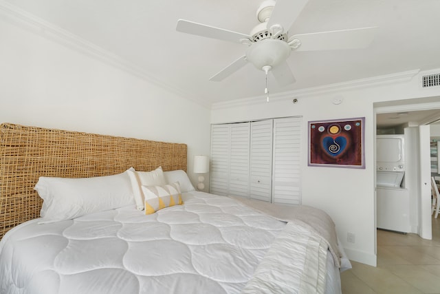 tiled bedroom with stacked washer / drying machine, a closet, ceiling fan, and ornamental molding