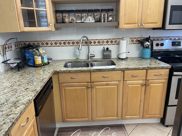 kitchen with appliances with stainless steel finishes, light stone countertops, sink, and tasteful backsplash