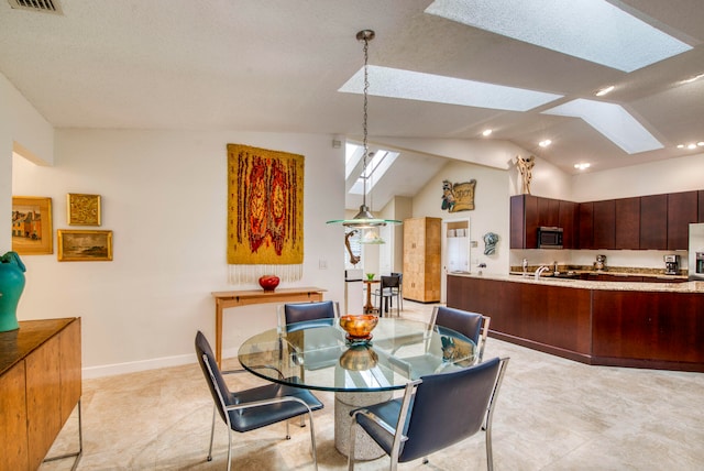 dining area featuring vaulted ceiling with skylight and a textured ceiling