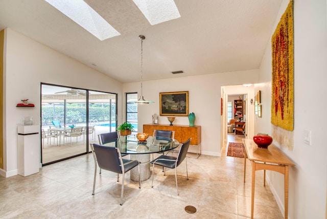 dining room with lofted ceiling with skylight and a textured ceiling