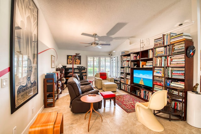 living area with ceiling fan, light tile patterned flooring, a textured ceiling, and vaulted ceiling