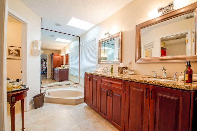 bathroom featuring a skylight, a textured ceiling, a washtub, tile patterned floors, and vanity