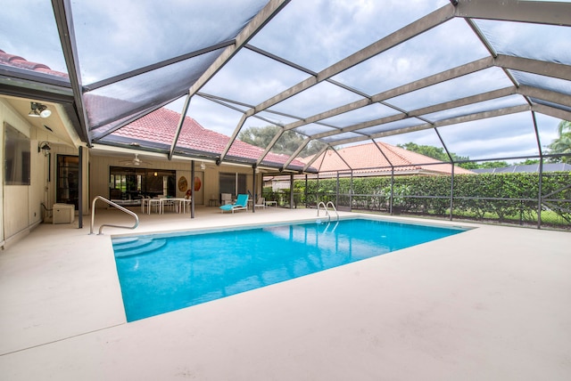 view of pool featuring a patio, glass enclosure, and ceiling fan