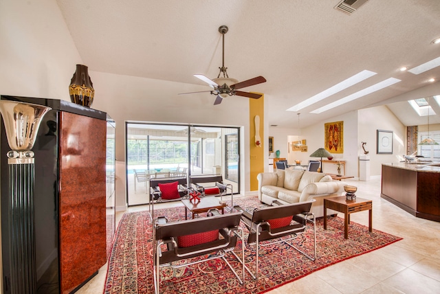 living room featuring ceiling fan, a textured ceiling, vaulted ceiling with skylight, and light tile patterned floors