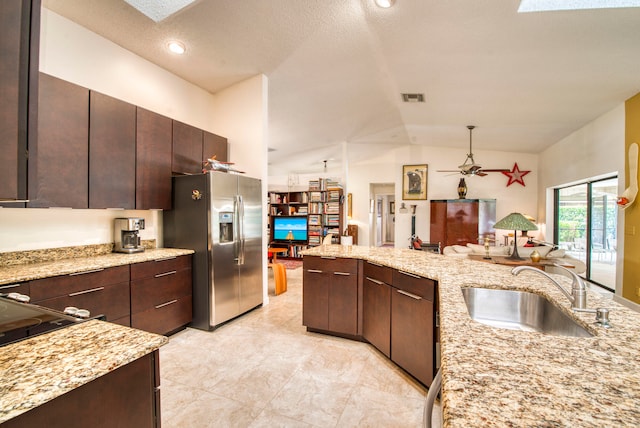 kitchen featuring sink, dark brown cabinets, vaulted ceiling with skylight, and stainless steel fridge with ice dispenser