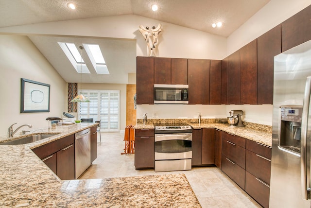 kitchen featuring lofted ceiling with skylight, stainless steel appliances, sink, and a textured ceiling