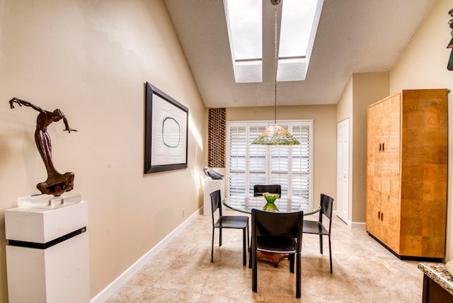 dining area featuring lofted ceiling with skylight and a textured ceiling