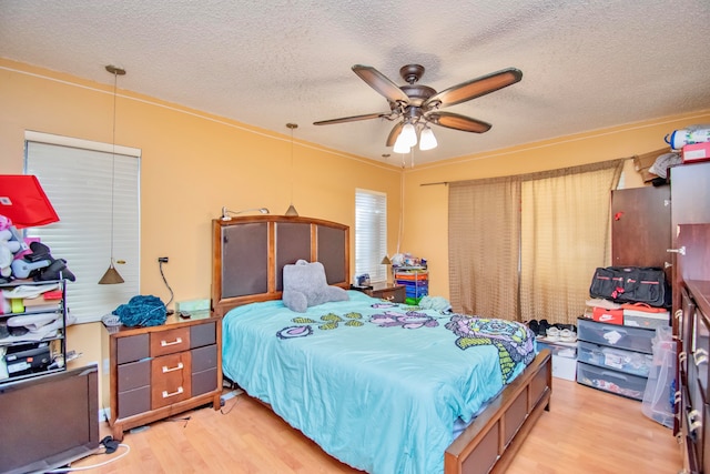 bedroom with ceiling fan, a textured ceiling, light hardwood / wood-style flooring, and ornamental molding