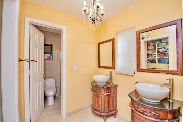 bathroom with an inviting chandelier, a textured ceiling, toilet, vanity, and tile patterned flooring