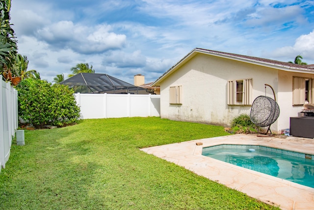 rear view of property featuring a fenced in pool, a yard, and glass enclosure