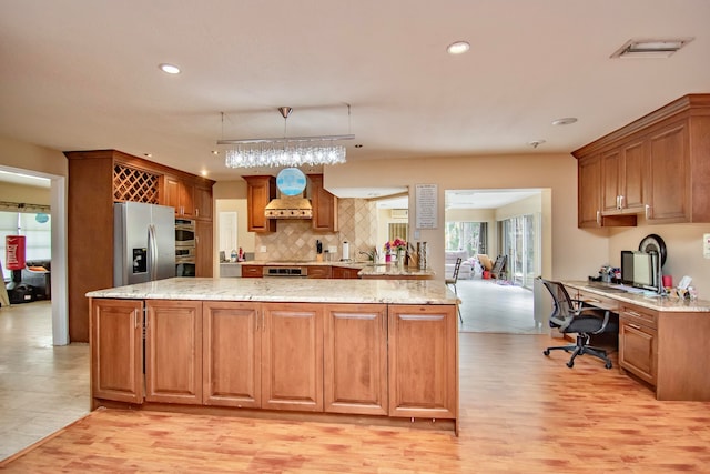 kitchen featuring light hardwood / wood-style flooring, stainless steel fridge, decorative light fixtures, and a kitchen island