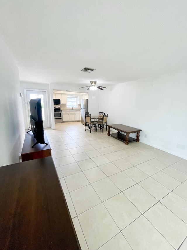 living area featuring light tile patterned floors and ceiling fan