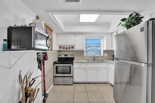 kitchen with light stone countertops, sink, light tile patterned floors, white cabinets, and appliances with stainless steel finishes