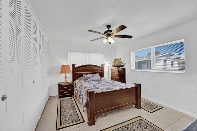 bedroom with light tile patterned flooring, ceiling fan, and a closet