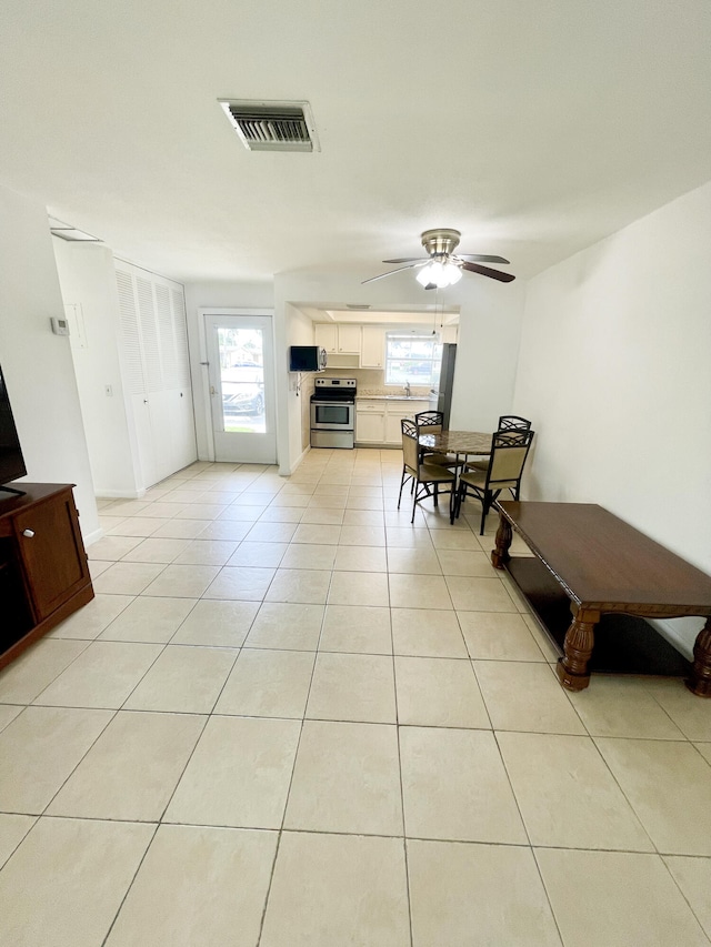 interior space with light tile patterned floors, a wealth of natural light, and ceiling fan