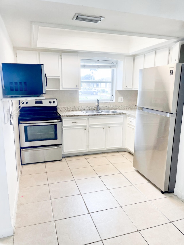 kitchen featuring stainless steel appliances, a tray ceiling, sink, and white cabinets