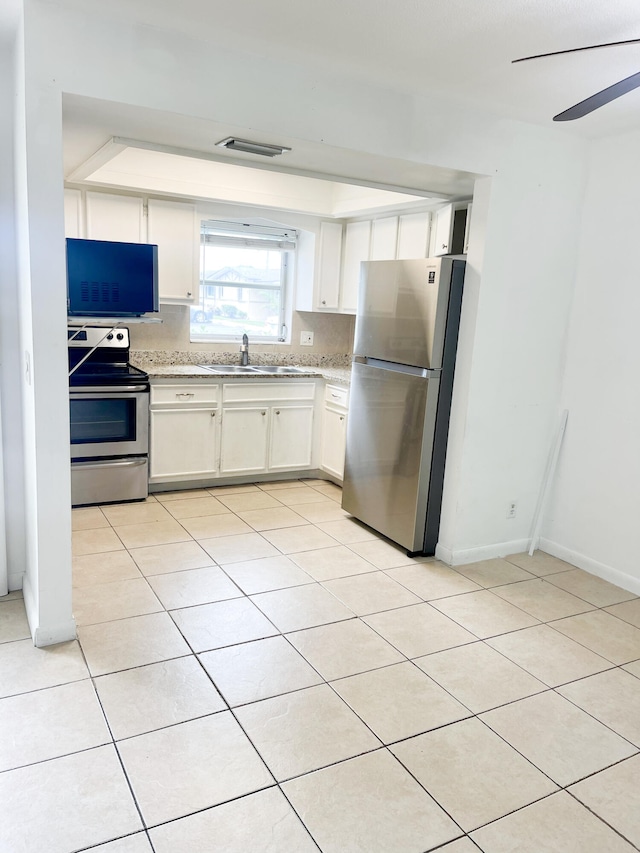 kitchen featuring sink, light tile patterned floors, appliances with stainless steel finishes, backsplash, and white cabinets