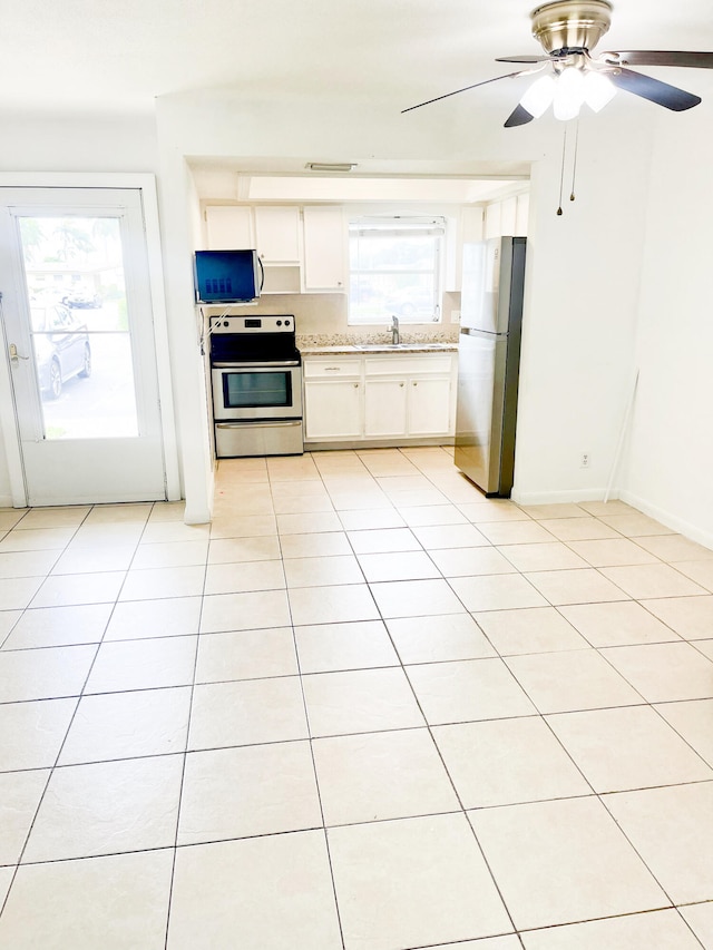 kitchen featuring light tile patterned flooring, a healthy amount of sunlight, stainless steel appliances, and white cabinets