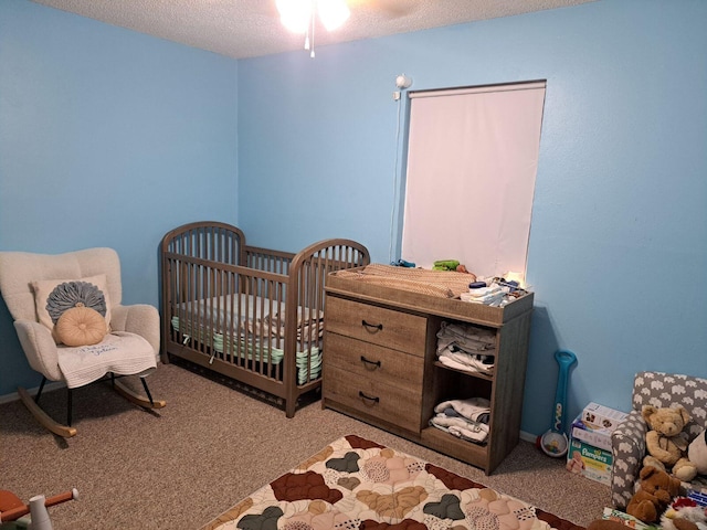 carpeted bedroom featuring a textured ceiling and a nursery area