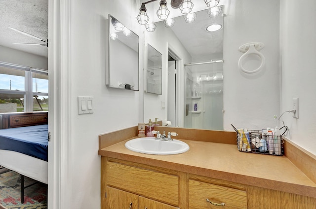 bathroom featuring ceiling fan, vanity, a textured ceiling, and walk in shower