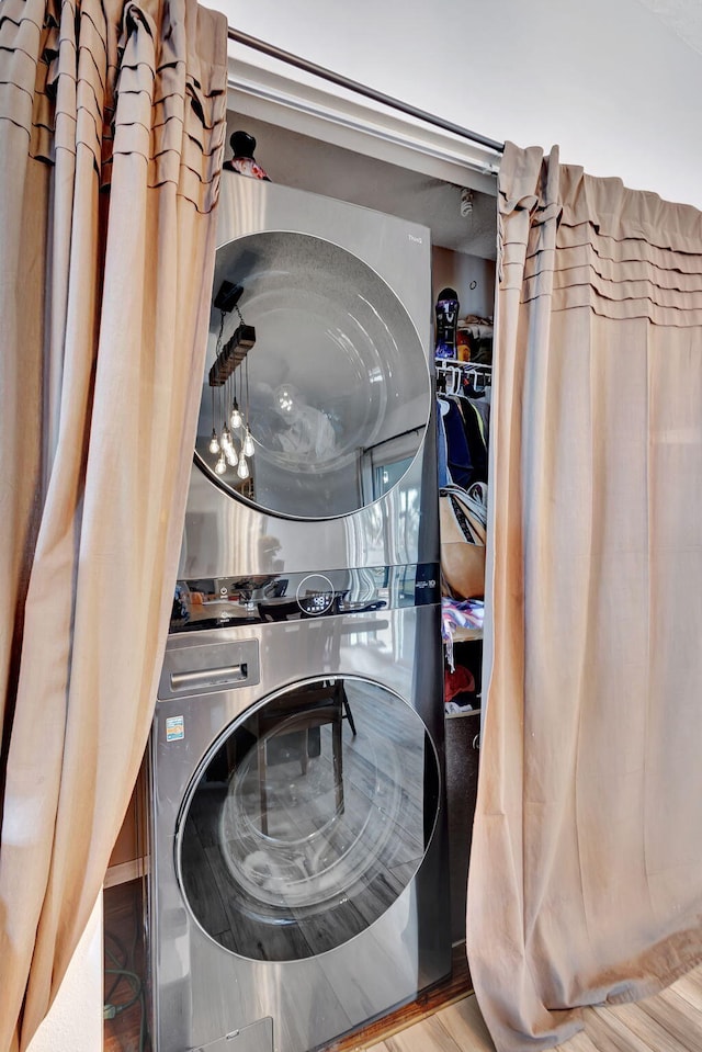 clothes washing area featuring hardwood / wood-style floors and stacked washer / drying machine