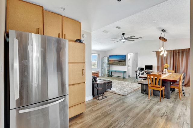 kitchen with lofted ceiling, ceiling fan with notable chandelier, light wood-type flooring, decorative light fixtures, and stainless steel refrigerator