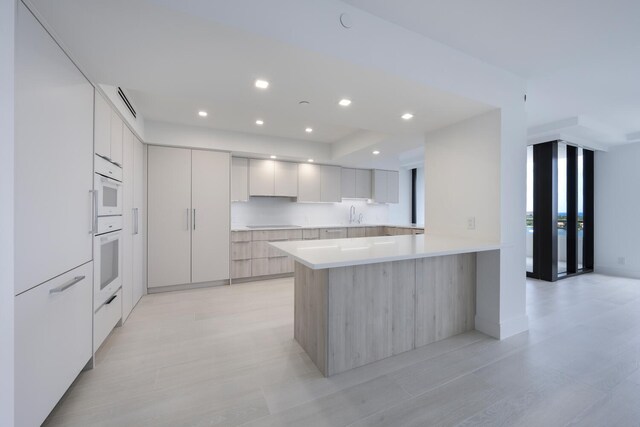 kitchen with white cabinets, a healthy amount of sunlight, a water view, and beverage cooler