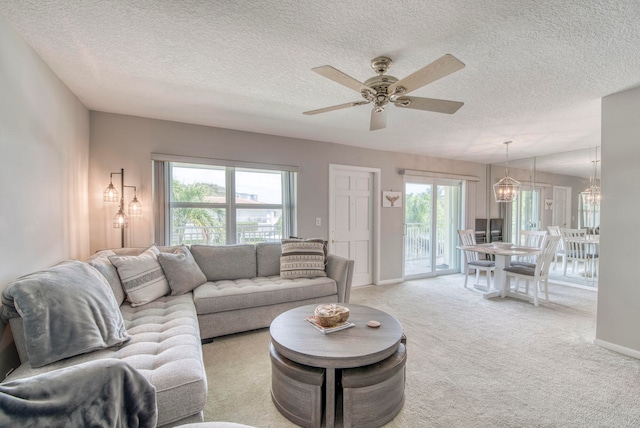 living room featuring a textured ceiling, ceiling fan with notable chandelier, and light carpet