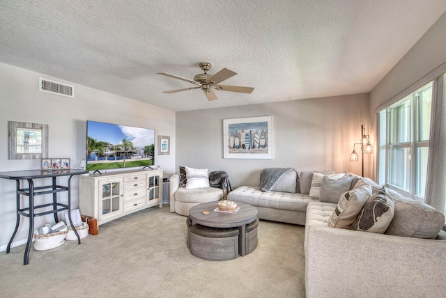 carpeted living room featuring plenty of natural light, ceiling fan, and a textured ceiling