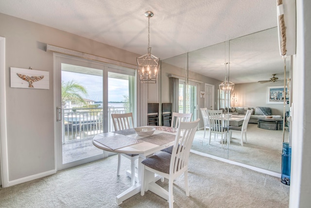 dining space with carpet flooring, ceiling fan with notable chandelier, and a textured ceiling