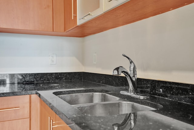 details featuring dark stone countertops, light brown cabinetry, and sink