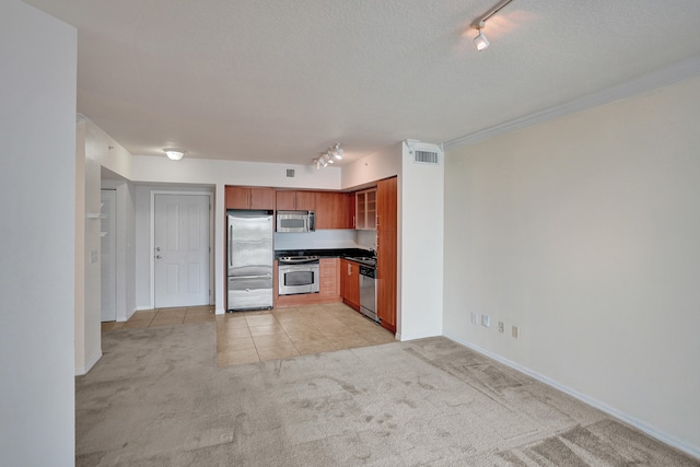 kitchen with light carpet, stainless steel appliances, sink, rail lighting, and a textured ceiling