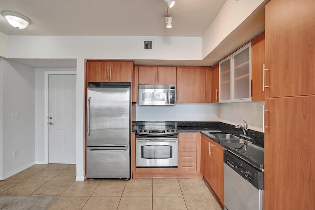 kitchen featuring sink, dark stone countertops, stainless steel appliances, and light tile patterned floors