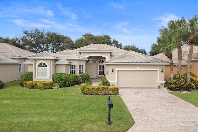 mediterranean / spanish house featuring a garage and a front yard