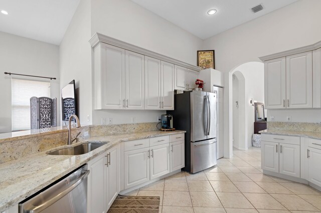 kitchen with stainless steel appliances, white cabinets, light tile patterned floors, sink, and decorative light fixtures