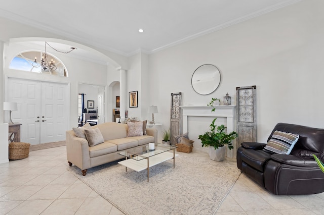 tiled living room with a fireplace, a towering ceiling, a chandelier, and crown molding