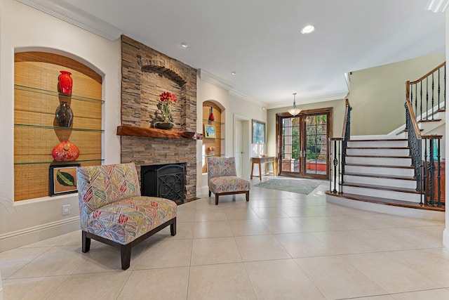 interior space featuring a stone fireplace, light tile patterned floors, crown molding, and french doors