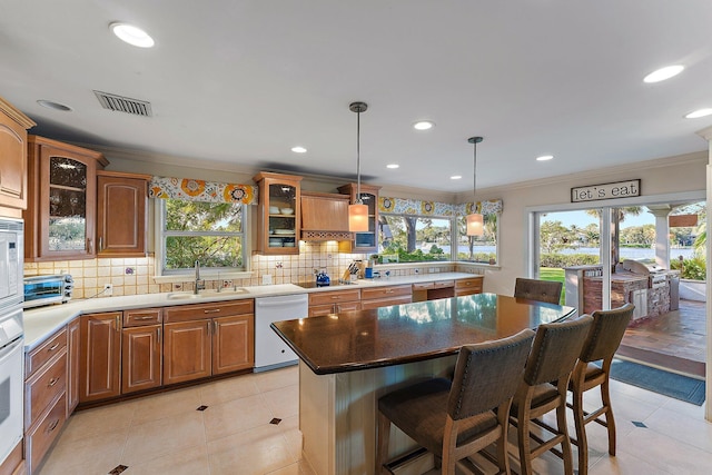 kitchen featuring sink, backsplash, white appliances, ornamental molding, and a kitchen island