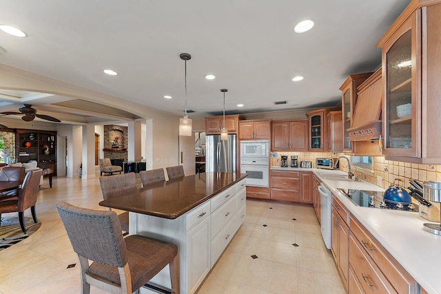 kitchen with white appliances, a center island, decorative light fixtures, tasteful backsplash, and sink