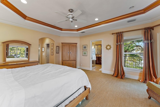 carpeted bedroom featuring ceiling fan, crown molding, ensuite bath, and a tray ceiling