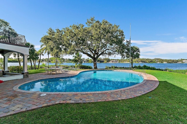 view of pool with a yard, a water view, and a patio