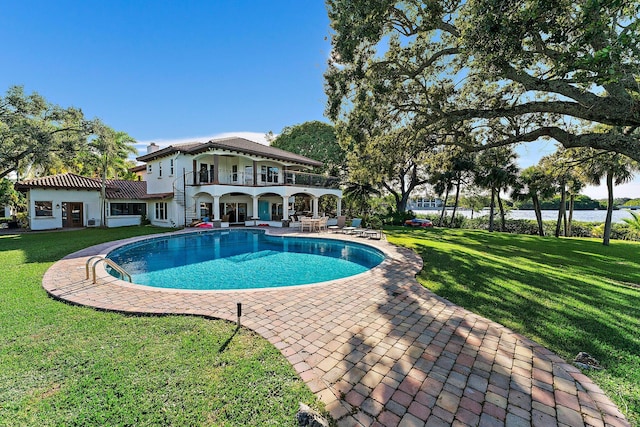 rear view of house with a balcony, a lawn, and a patio area