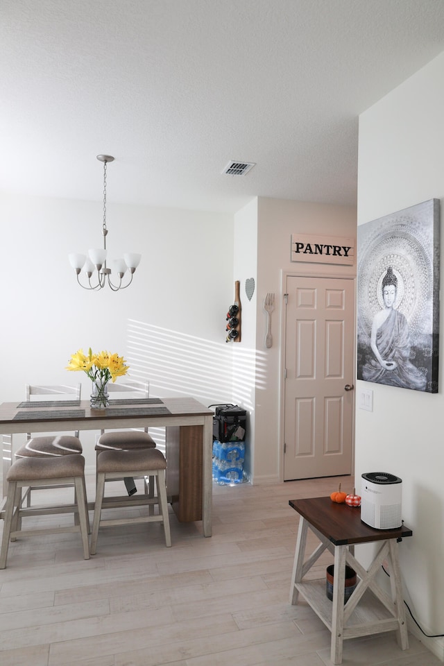 dining space featuring light hardwood / wood-style flooring and an inviting chandelier