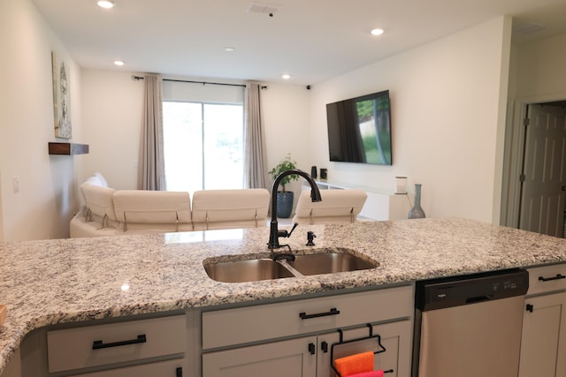 kitchen with dishwasher, light stone countertops, and sink