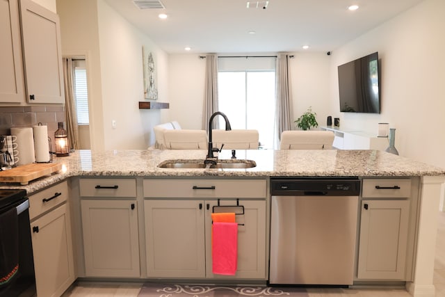 kitchen featuring light stone countertops, sink, dishwasher, backsplash, and kitchen peninsula