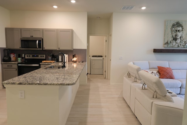 kitchen featuring appliances with stainless steel finishes, sink, washer / dryer, and gray cabinetry